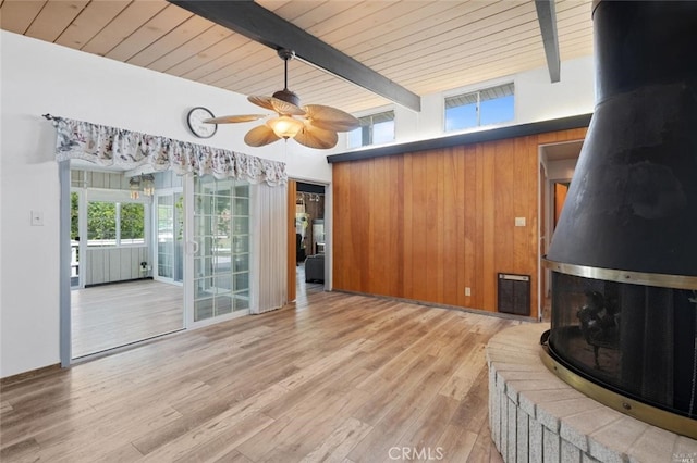 unfurnished living room with wooden walls, light hardwood / wood-style floors, wooden ceiling, and beamed ceiling