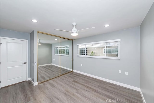 unfurnished bedroom featuring hardwood / wood-style floors, ceiling fan, and a closet