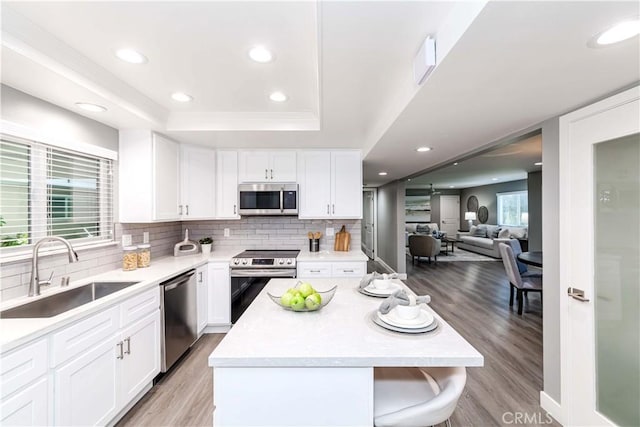 kitchen featuring sink, a raised ceiling, white cabinets, and appliances with stainless steel finishes