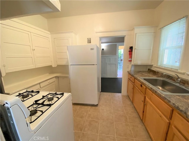 kitchen with sink, white appliances, light tile patterned floors, and white cabinets