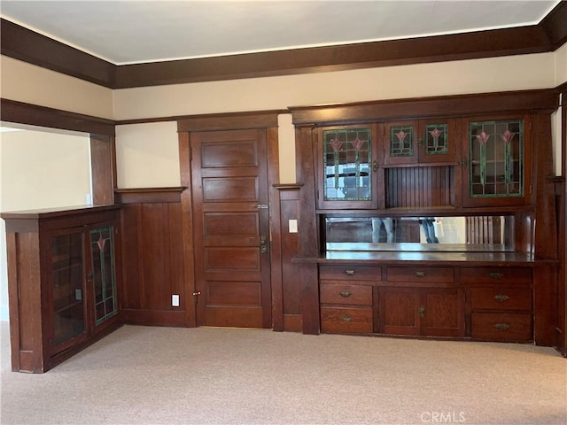 kitchen featuring light colored carpet, wood walls, and dark brown cabinets