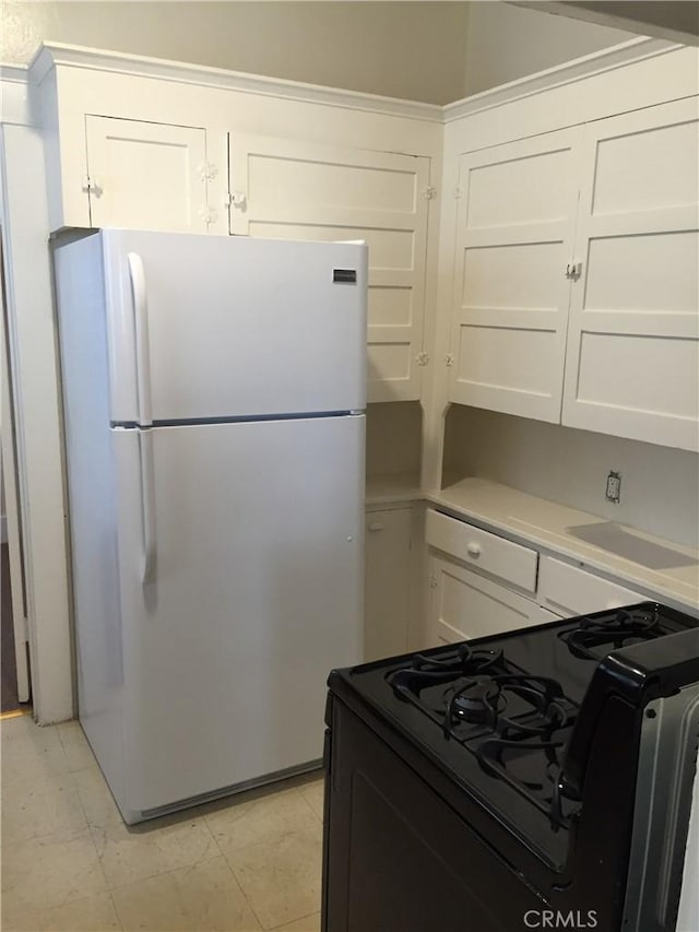 kitchen featuring white fridge, white cabinetry, and gas stove