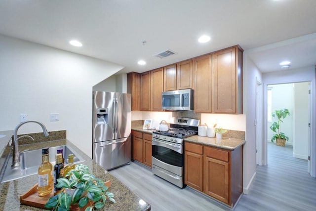 kitchen featuring light stone countertops, sink, light hardwood / wood-style flooring, and stainless steel appliances