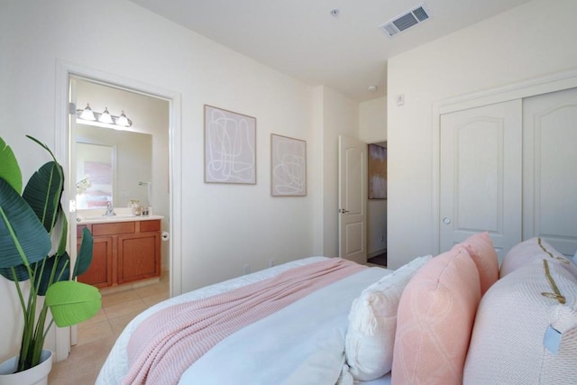 bedroom featuring ensuite bathroom, light tile patterned floors, a closet, and sink