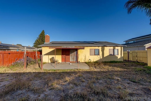 rear view of property featuring solar panels and a patio