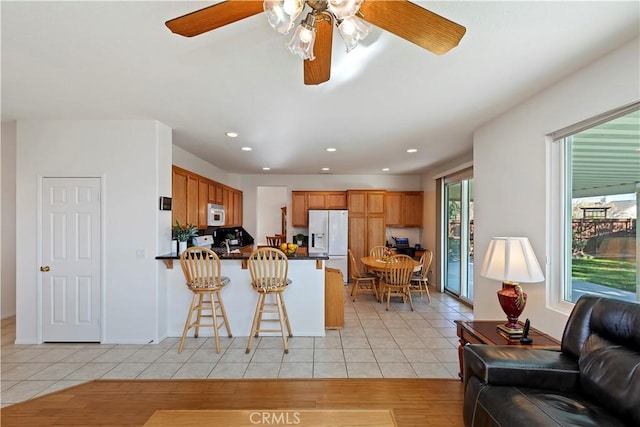 kitchen with white appliances, ceiling fan, light tile patterned flooring, and kitchen peninsula