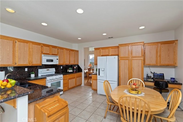 kitchen with white appliances, light tile patterned floors, backsplash, dark stone countertops, and sink