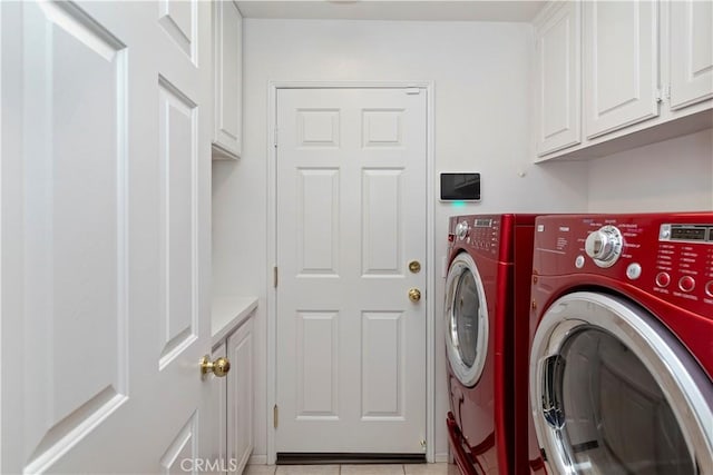 laundry room featuring light tile patterned floors, separate washer and dryer, and cabinets