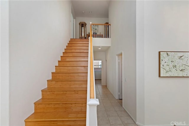 stairway with a high ceiling and tile patterned floors