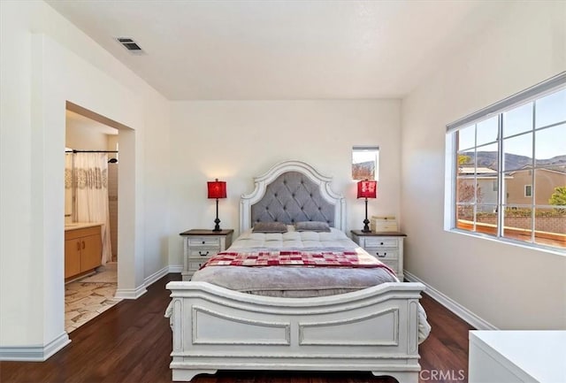 bedroom featuring connected bathroom and dark hardwood / wood-style floors