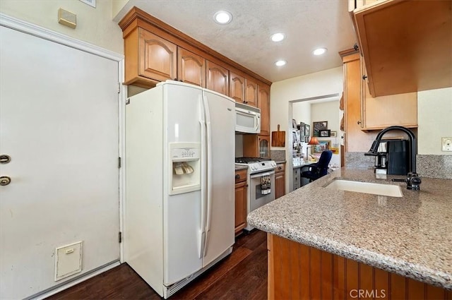 kitchen with white appliances, light stone countertops, dark hardwood / wood-style floors, and sink