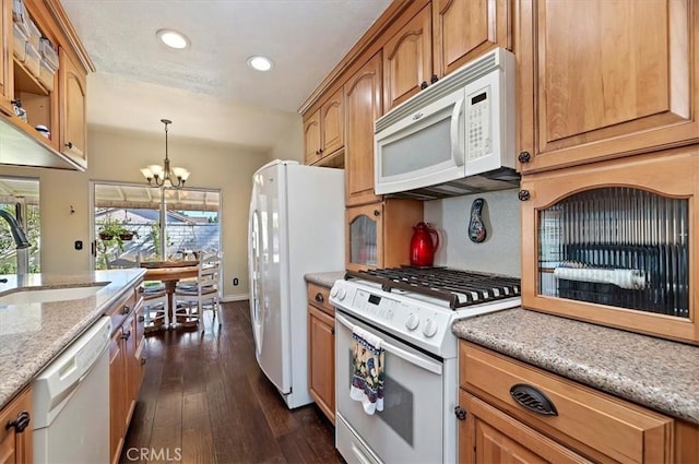 kitchen featuring white appliances, pendant lighting, a chandelier, dark hardwood / wood-style flooring, and sink