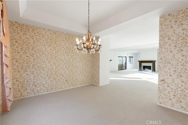 unfurnished dining area with carpet floors, an inviting chandelier, and a tray ceiling