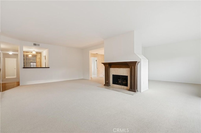 unfurnished living room with a tiled fireplace and light carpet