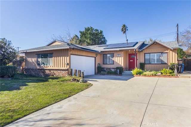 ranch-style home with concrete driveway, an attached garage, a front yard, brick siding, and solar panels