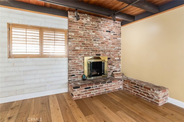 unfurnished living room with a brick fireplace, hardwood / wood-style floors, wooden ceiling, and beam ceiling