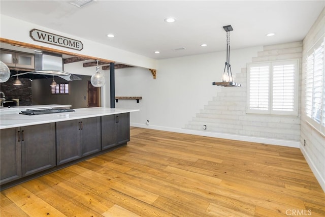 kitchen featuring extractor fan, light hardwood / wood-style flooring, pendant lighting, stainless steel gas cooktop, and dark brown cabinetry