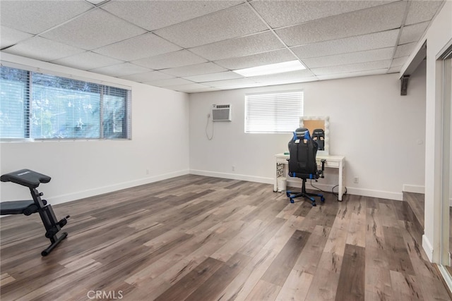 office with a paneled ceiling, a wall mounted air conditioner, and wood-type flooring