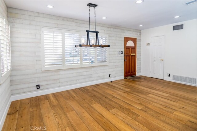 unfurnished dining area with a chandelier and hardwood / wood-style floors