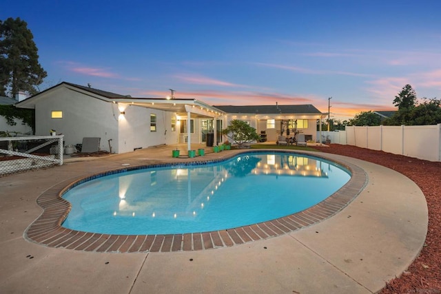 pool at dusk featuring a patio