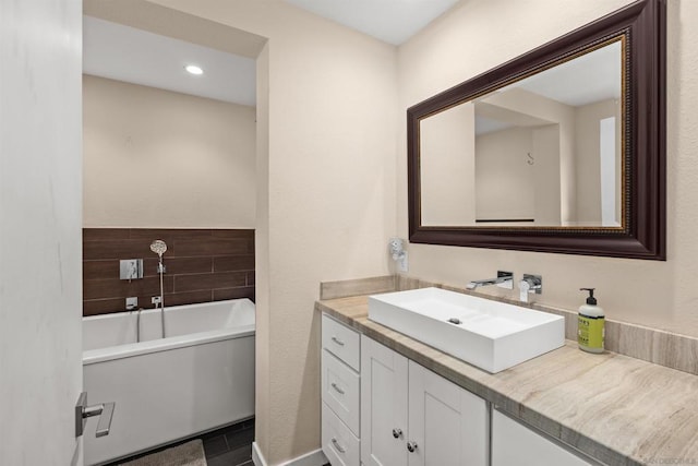 bathroom with a washtub, tile patterned floors, and vanity