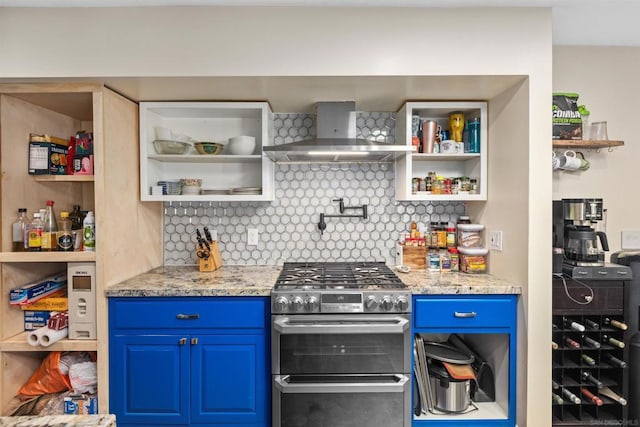 kitchen with blue cabinets, wall chimney exhaust hood, decorative backsplash, range with two ovens, and light stone countertops