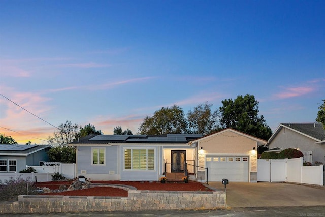 ranch-style home with a garage and solar panels