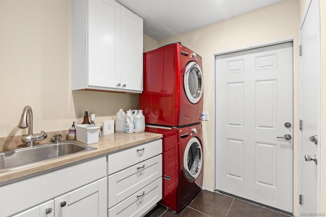 clothes washing area featuring sink, stacked washer and clothes dryer, dark tile patterned flooring, and cabinets