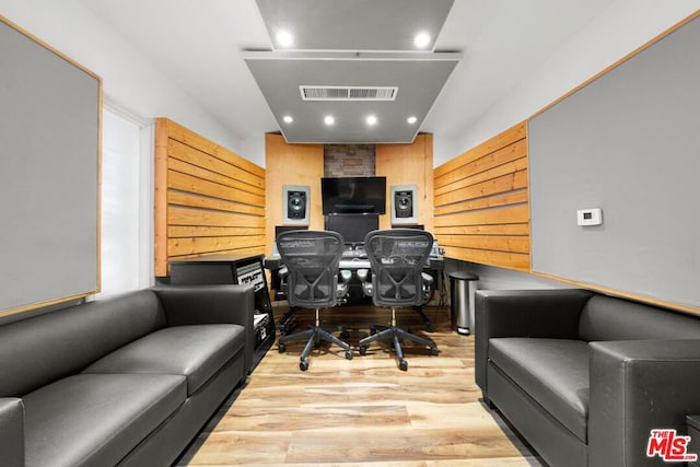 office area with light hardwood / wood-style floors and wooden walls