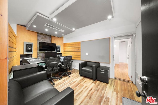 home office with wood walls and light hardwood / wood-style floors