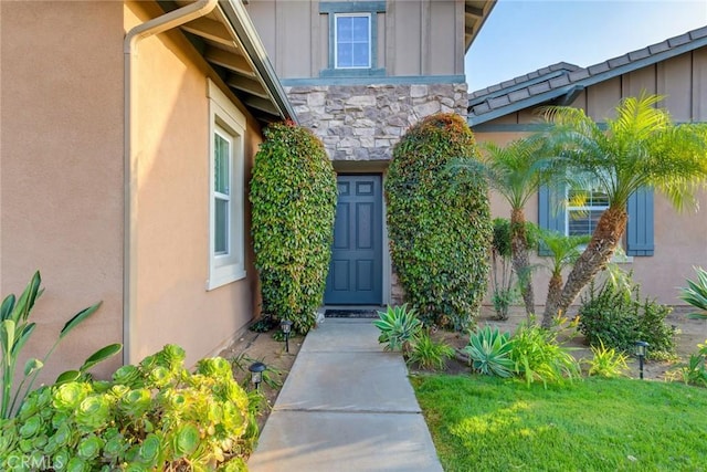 doorway to property with stone siding, stucco siding, and board and batten siding