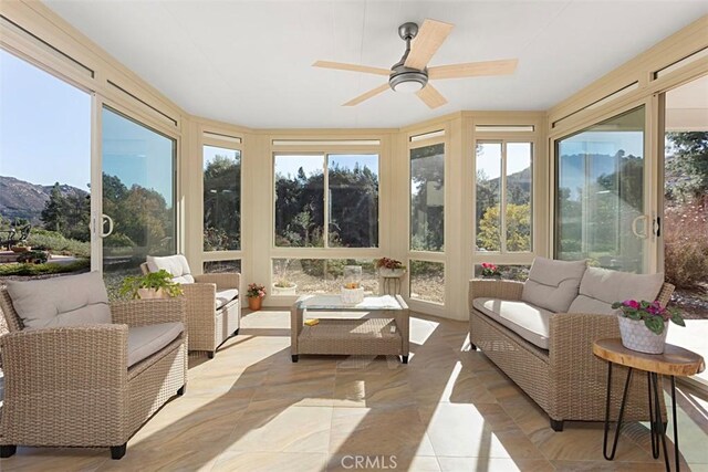 sunroom with ceiling fan and a mountain view