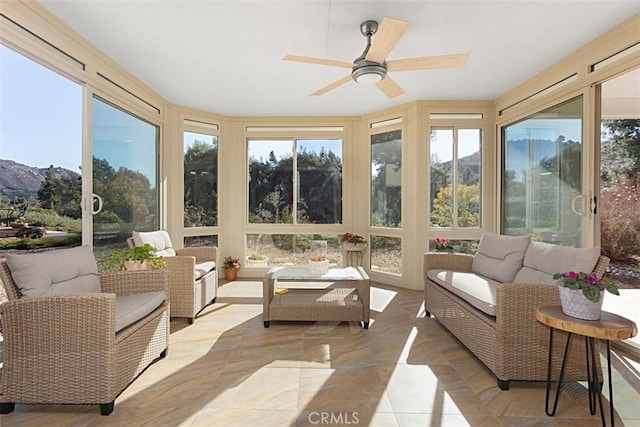 sunroom featuring ceiling fan and a mountain view