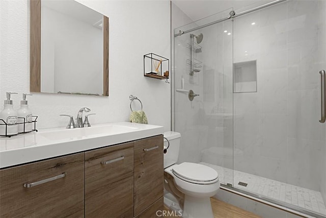 bathroom with toilet, vanity, and an enclosed shower