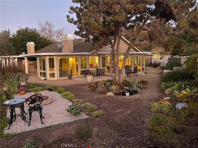 back house at dusk featuring outdoor lounge area and a patio