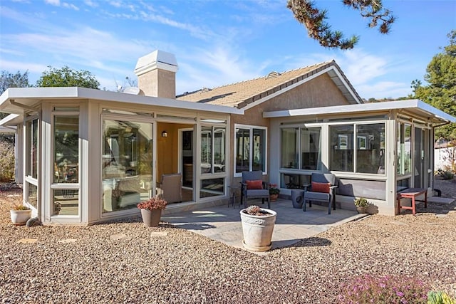 rear view of house featuring a sunroom and a patio