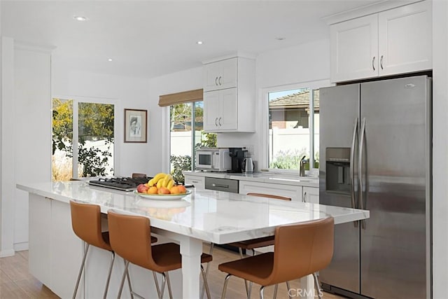 kitchen featuring stainless steel appliances, white cabinets, light stone counters, and sink