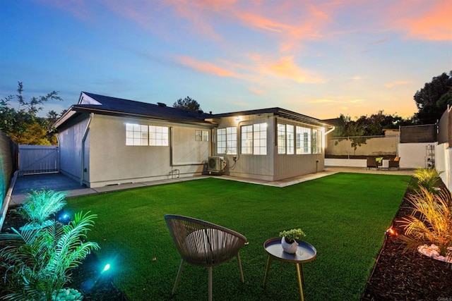 back house at dusk with a patio area and a yard