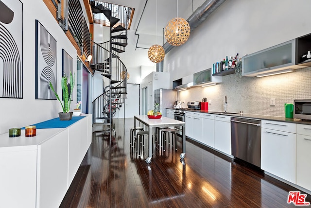 kitchen with decorative light fixtures, decorative backsplash, white cabinets, appliances with stainless steel finishes, and sink