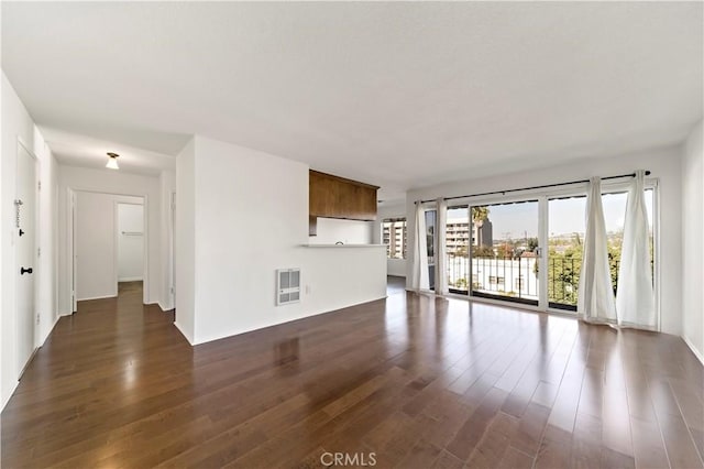 unfurnished living room featuring dark wood-type flooring and a wealth of natural light