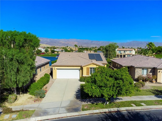 view of front of property with solar panels, a garage, and a mountain view