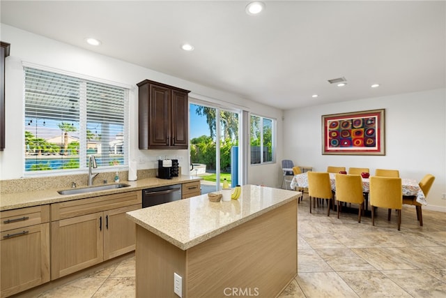 kitchen featuring a center island, light stone countertops, dishwasher, and sink