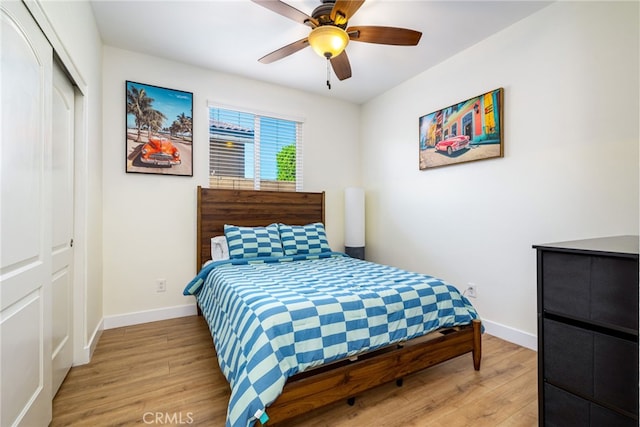 bedroom with light wood-type flooring, ceiling fan, and a closet