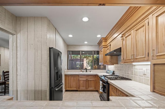 kitchen featuring light tile patterned flooring, range with gas stovetop, tasteful backsplash, sink, and stainless steel refrigerator with ice dispenser