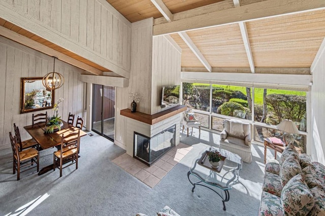 carpeted living room featuring a notable chandelier, wood ceiling, wooden walls, and lofted ceiling with beams