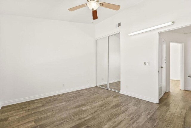 unfurnished bedroom with ceiling fan, a closet, and wood-type flooring