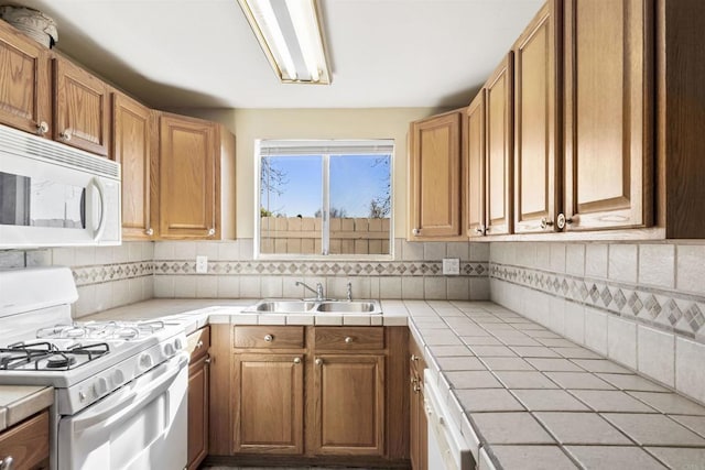 kitchen featuring white appliances, tile countertops, backsplash, and sink