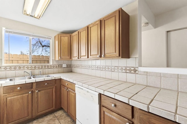 kitchen featuring sink, dishwasher, light tile patterned flooring, tile counters, and backsplash