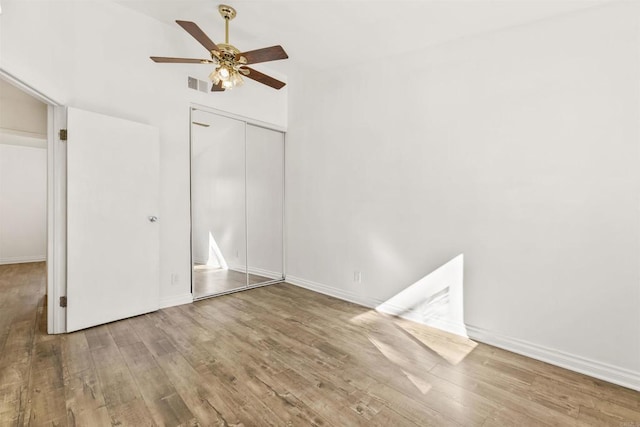 unfurnished bedroom with wood-type flooring, ceiling fan, and a closet