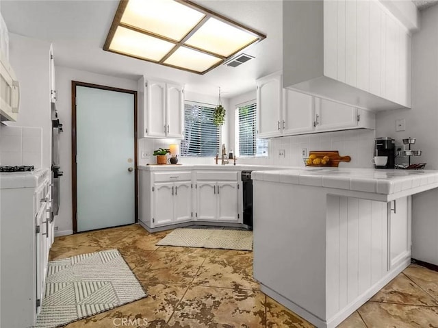 kitchen featuring white cabinetry, tasteful backsplash, tile countertops, and kitchen peninsula